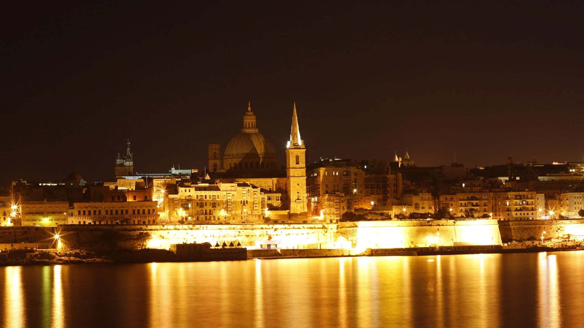 Valletta's illuminated skyline at night seen across the water from Sliema, Malta