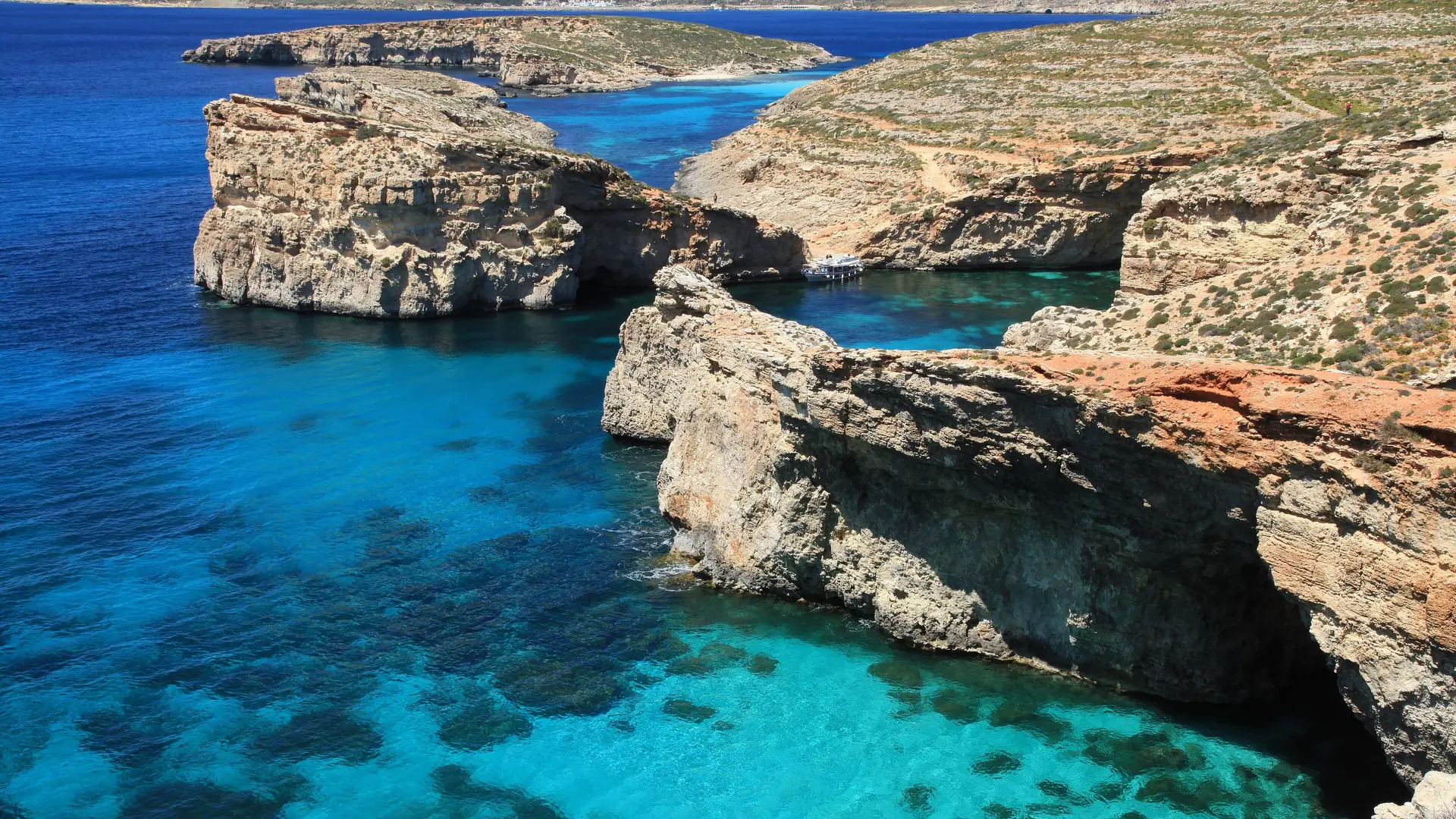 Boats anchored on the bright turquoise water of the Blue Lagoon at Comino, Malta