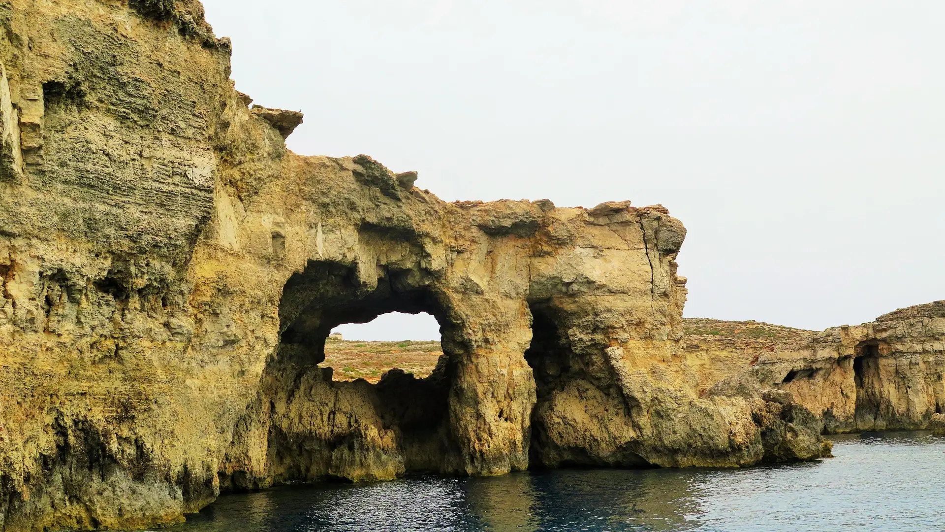 Rocky coastline of Comino island, Malta, with clear turquoise water and limestone cliffs