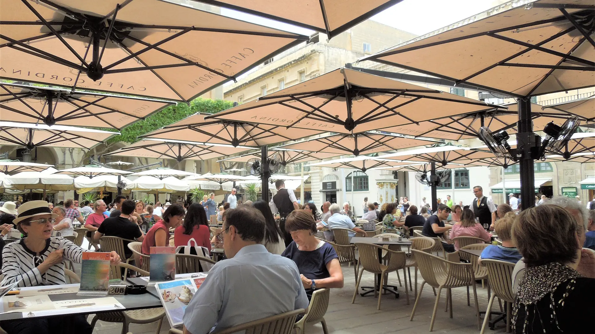 Diners at a busy café terrace in a Valletta square, Malta