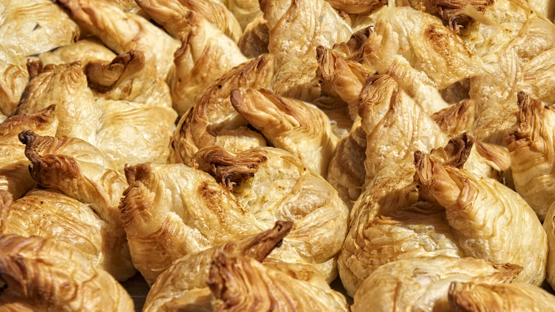 A tray of freshly baked golden pastizzi, Malta's flaky filled pastry