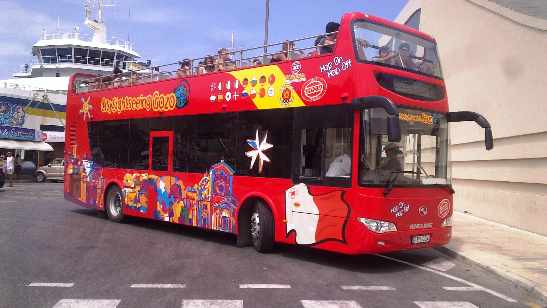A red open-top City Sightseeing hop-on hop-off bus on a Malta road, Malta