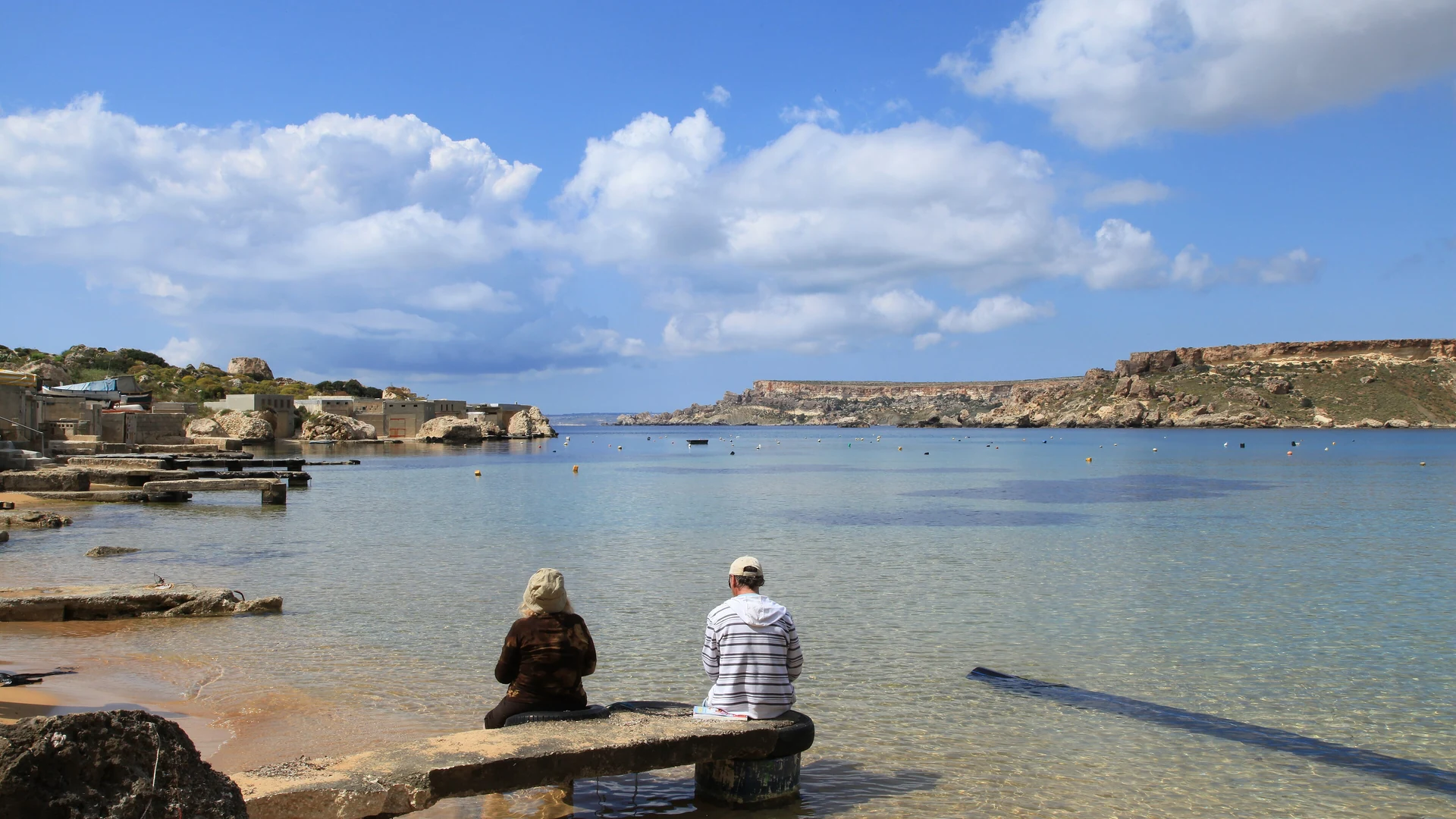 The calm, clear shallows of Gnejna Bay on Malta's northwest coast under a bright spring sky