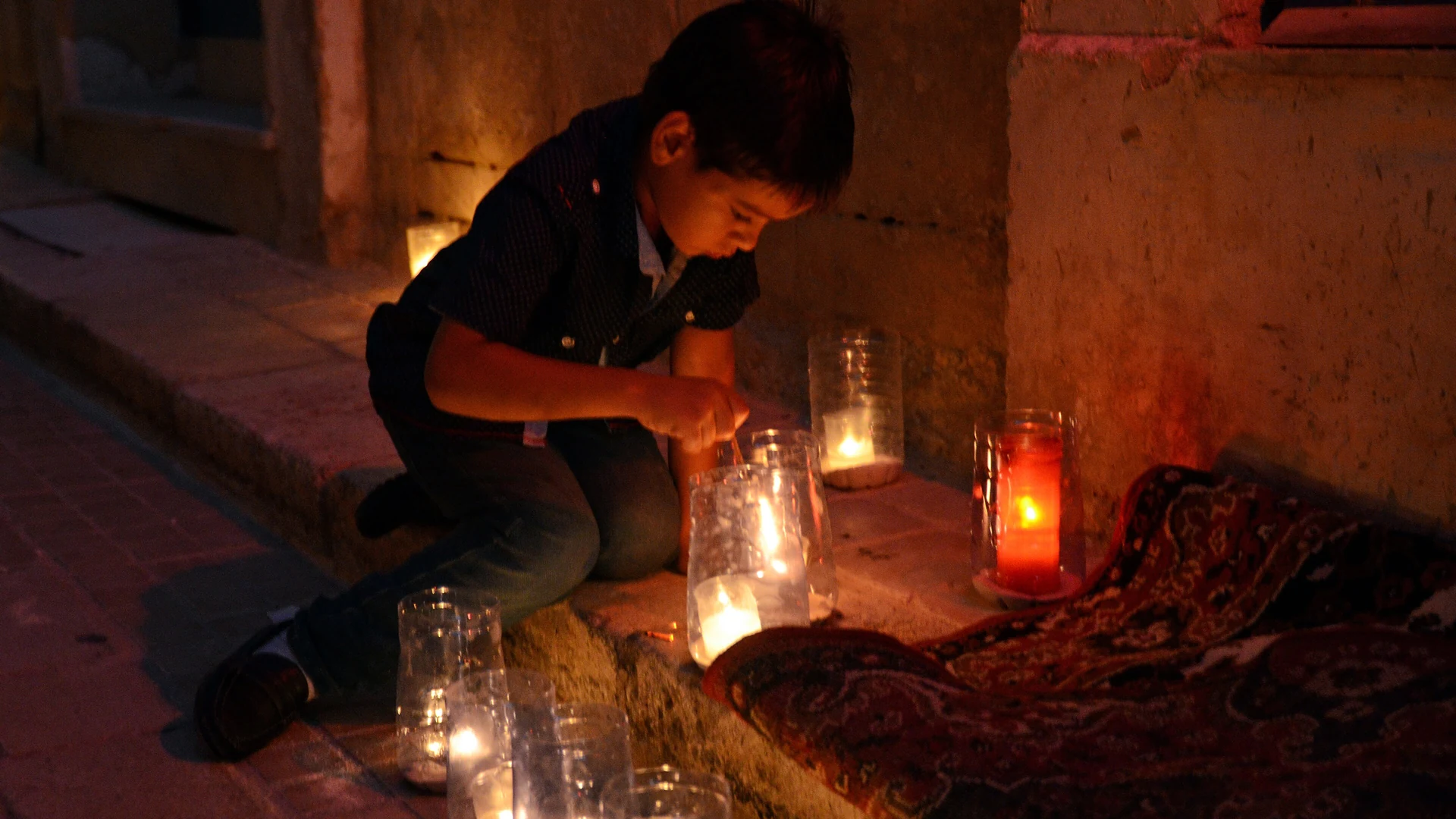 A child lighting candles in jars during the Birgu by Candlelight event in October, Malta