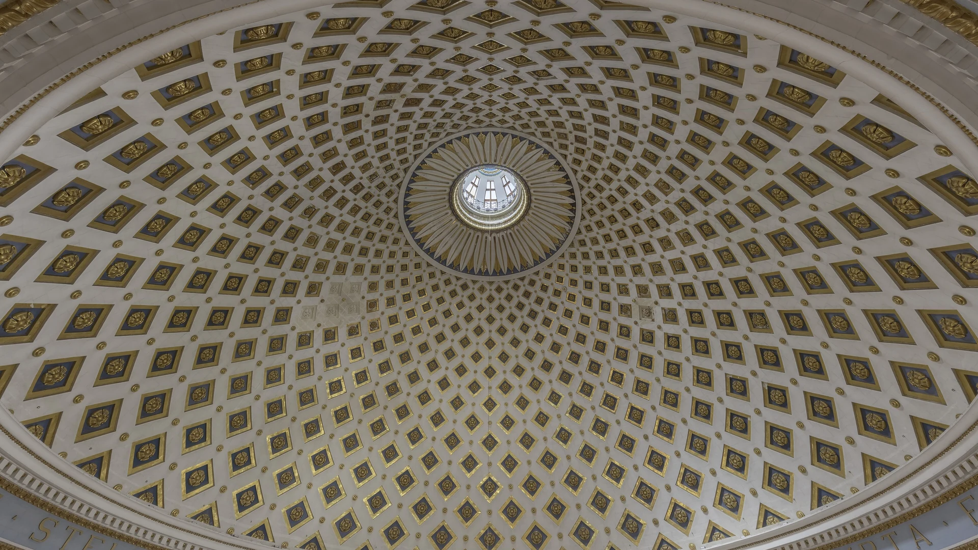 The vast interior of the Mosta Rotunda, with its enormous dome, ornate decorations and rows of pews below