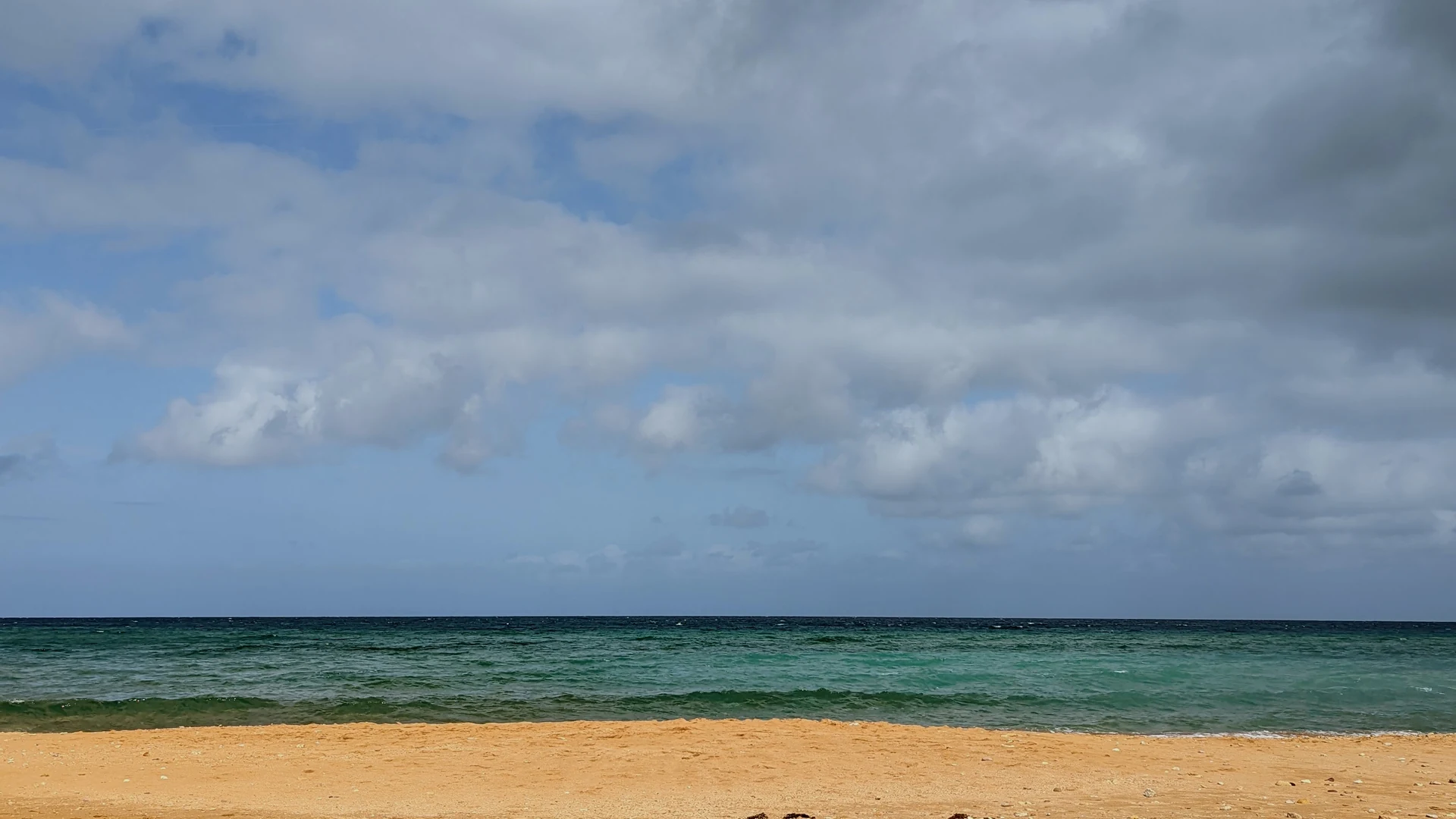 Ramla Bay's distinctive orange-red sand beach with clear blue water on the north coast of Gozo, Malta
