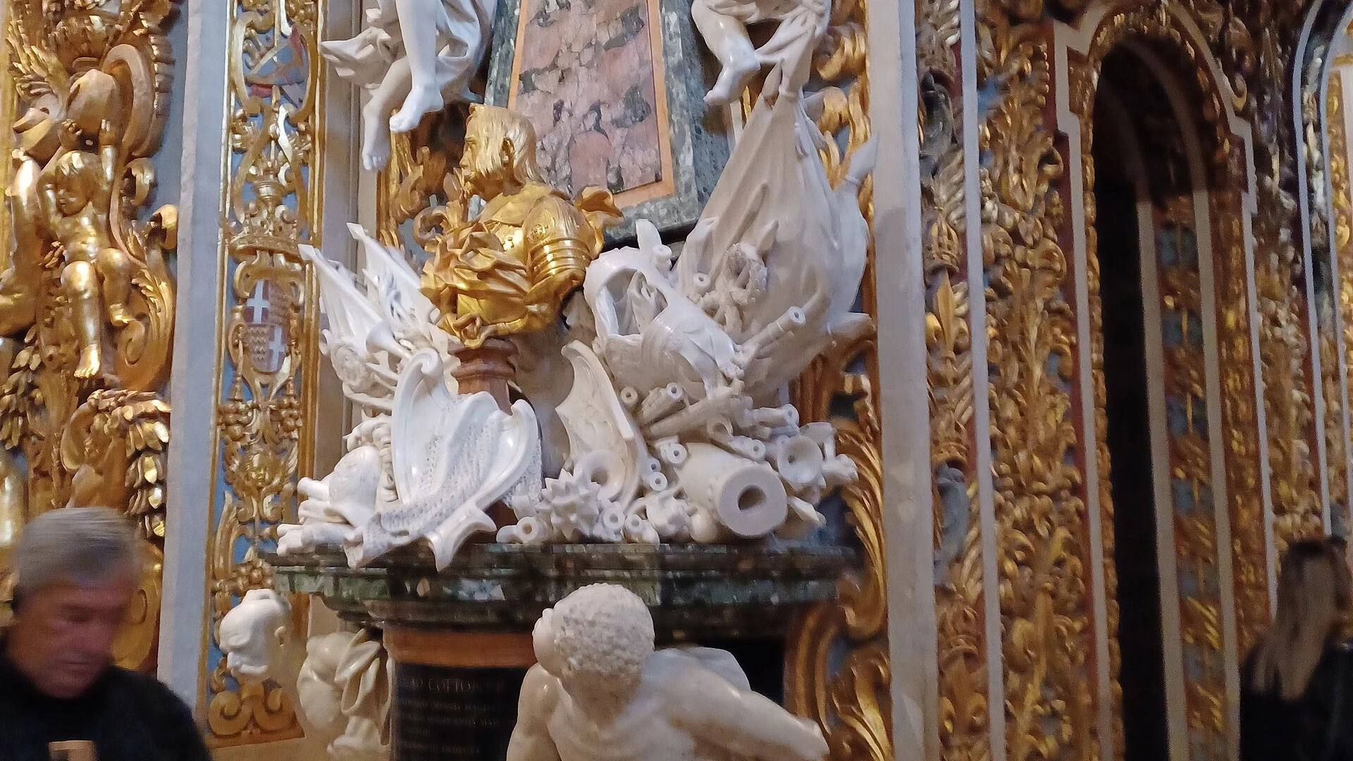The ornate Baroque interior nave of St John's Co-Cathedral in Valletta, Malta, with gilded carvings and marble floor tombstones