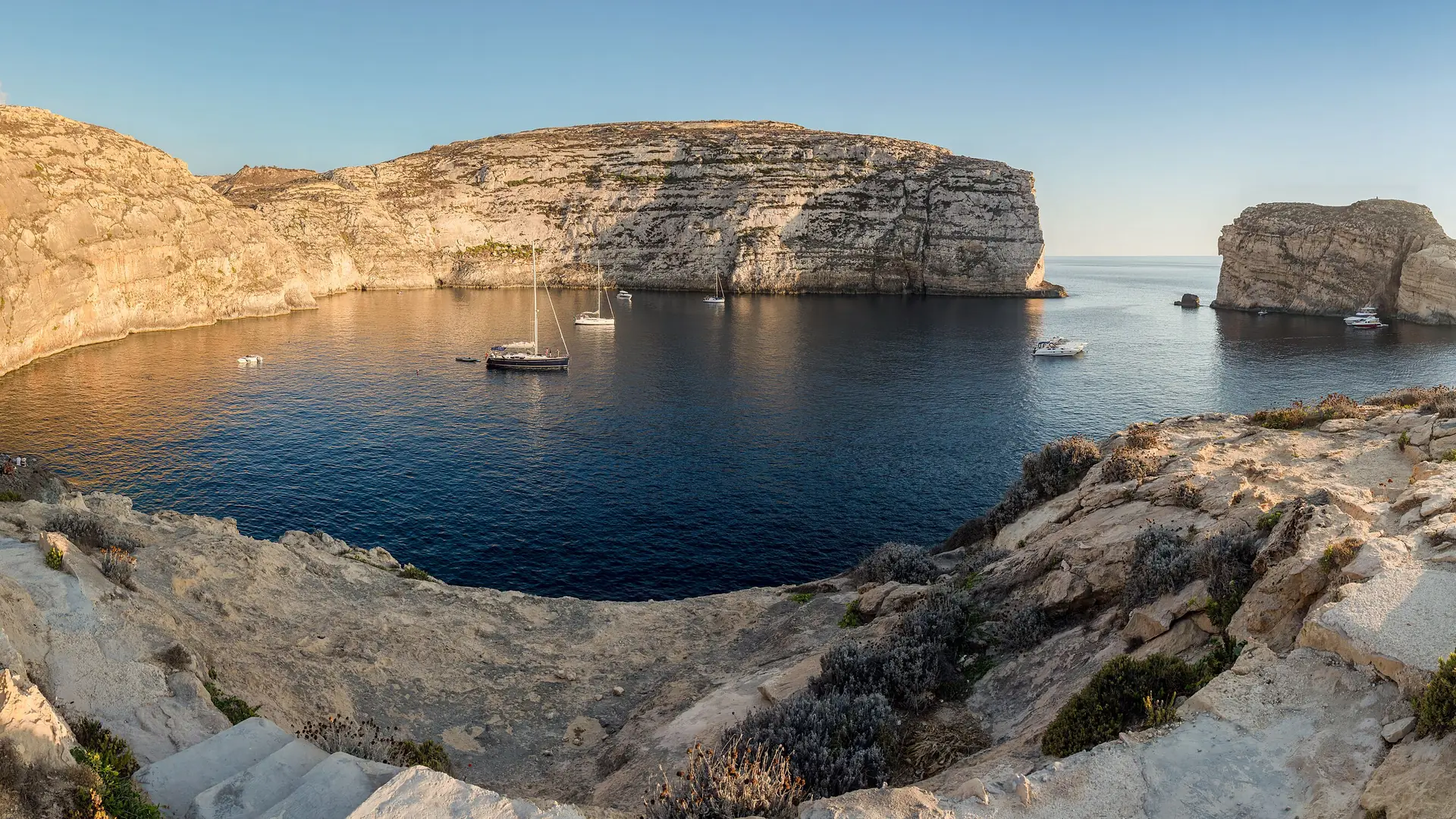 Dwejra Bay on Gozo with the cliffs and Fungus Rock, yachts anchored in the deep blue water