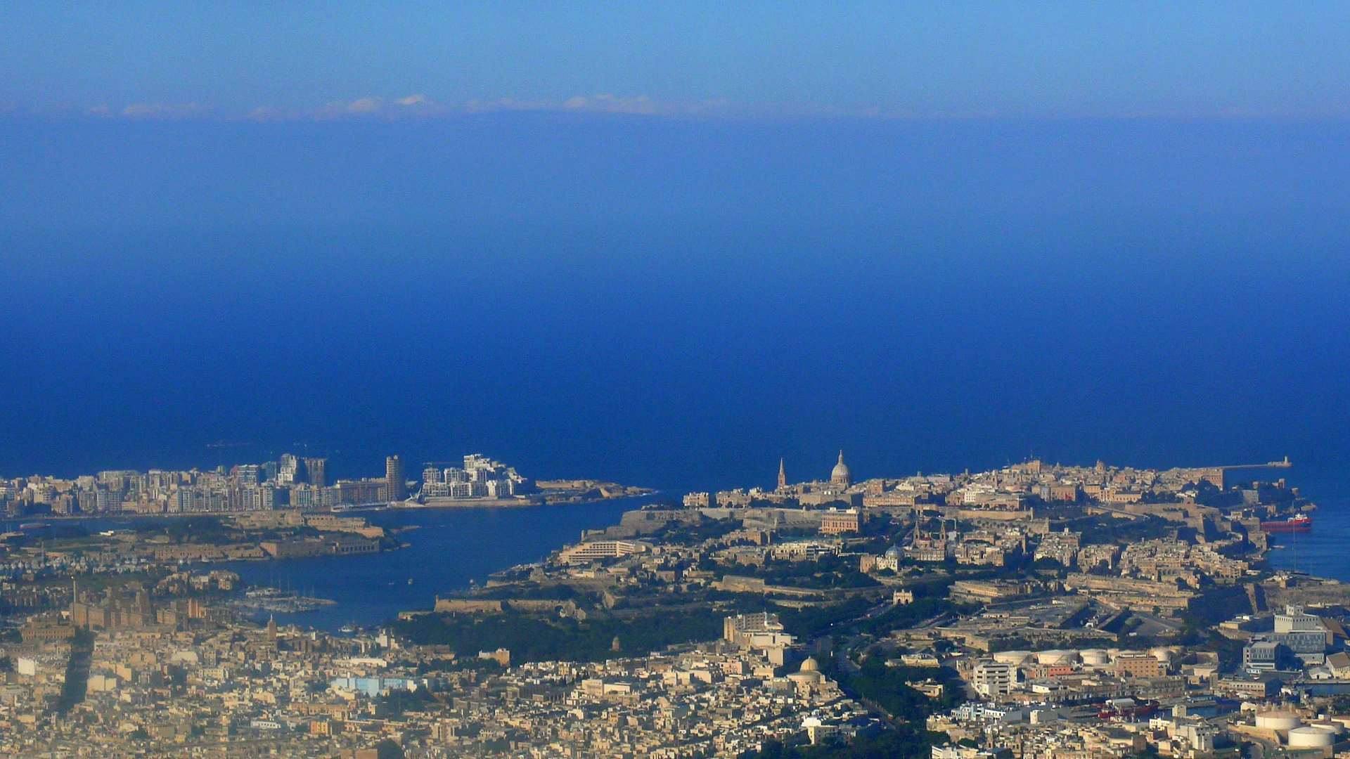 Aerial view of Malta's harbour region and coastline meeting the deep blue Mediterranean Sea